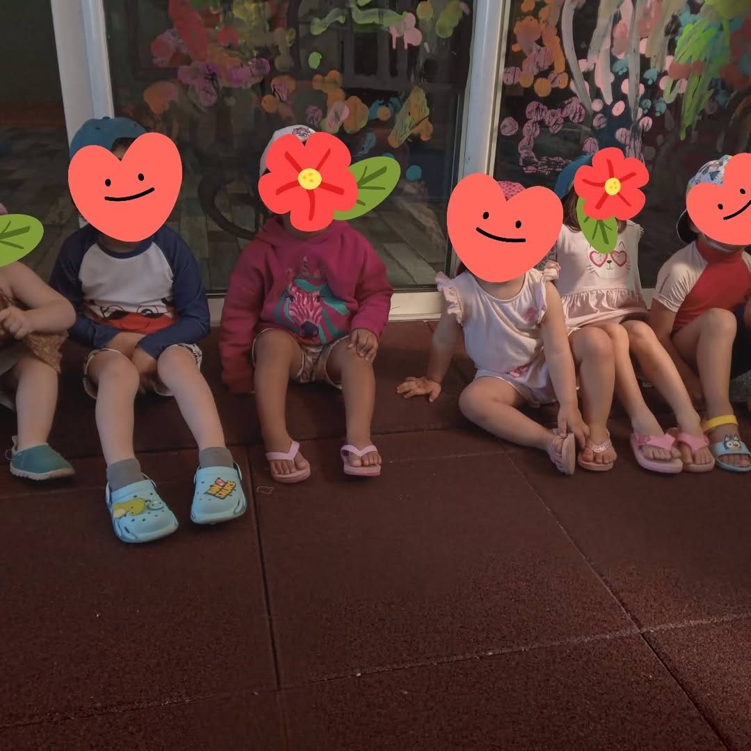 Des enfants assis côte à côte, visages masqués par des cœurs et des fleurs dessinés